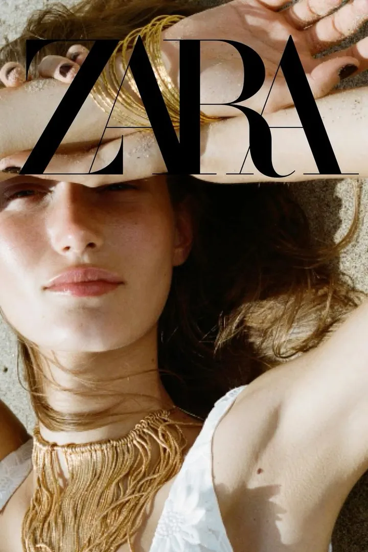 Imagen de campaña de Zara: modelo tumbada en la arena con pulseras y collar dorados bajo el logotipo de Zara